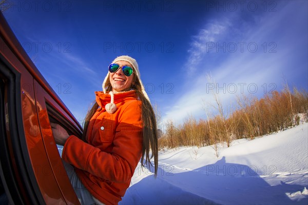 Caucasian woman leaning out car window in snowy field