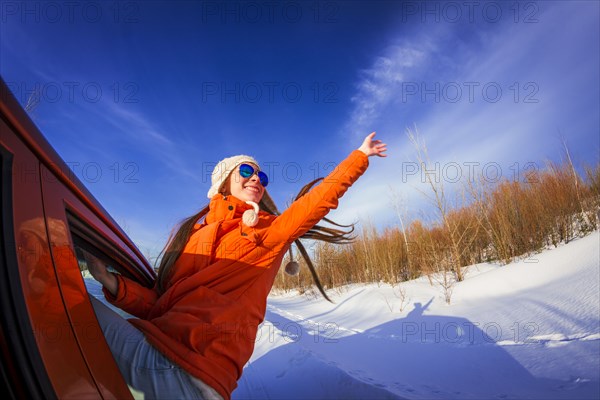Caucasian woman leaning out car window in snowy field