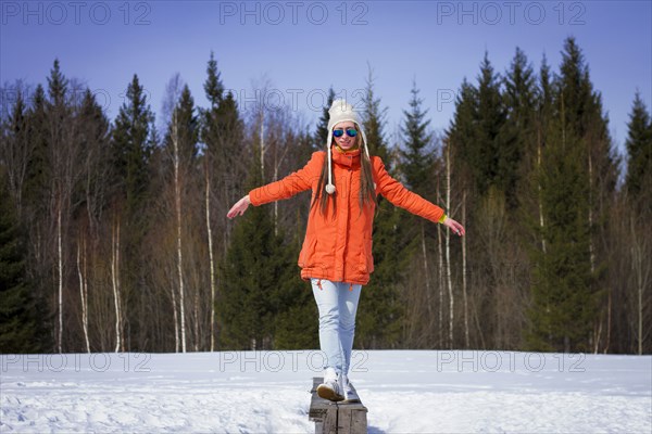 Caucasian woman balancing on wooden bench in snowy field