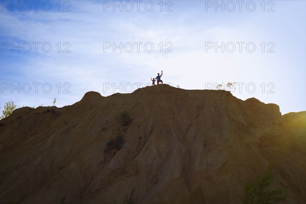 People standing on hilltop under blue sky