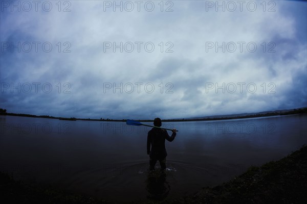 Caucasian man standing in still remote lake