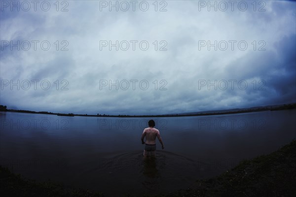 Caucasian man standing in still remote lake