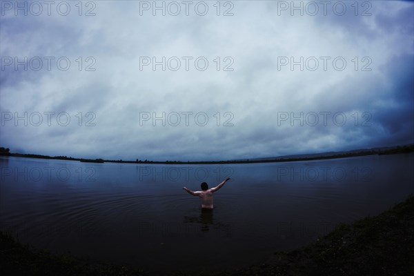 Caucasian man standing in still remote lake