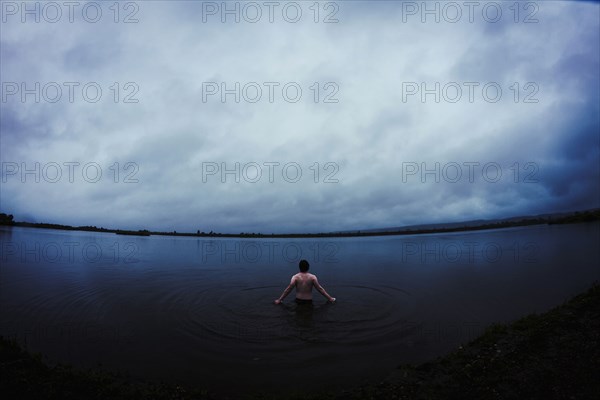 Caucasian man standing in still remote lake