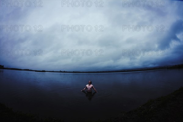 Caucasian man standing in still remote lake