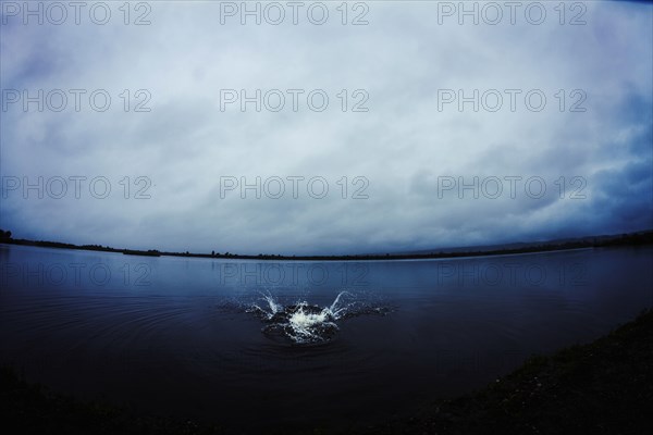 Caucasian man splashing in still remote lake