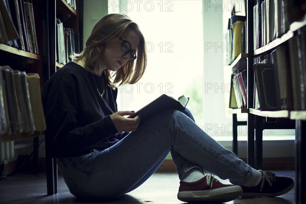 Caucasian woman reading book in library