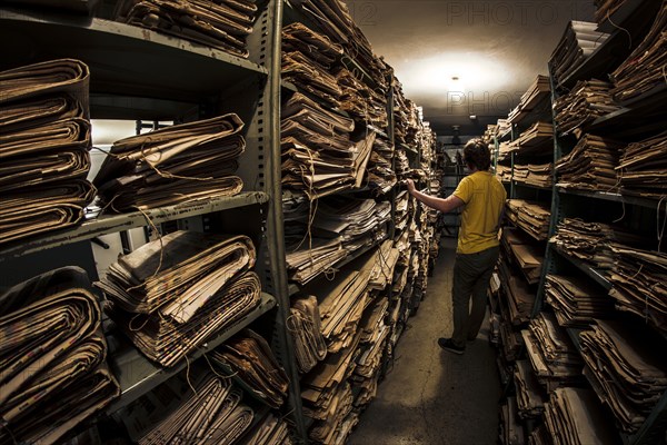 Caucasian man searching old newspapers in library archive