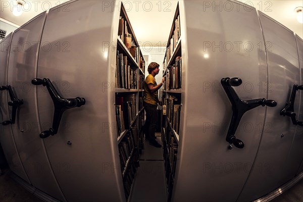 Caucasian man searching old newspapers in library archive