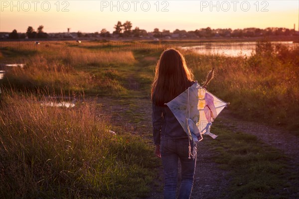 Caucasian teenage girl carrying kite on dirt path
