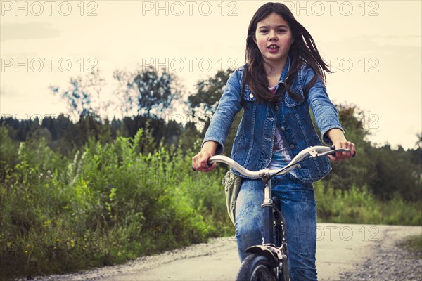 Caucasian teenage girl riding bicycle