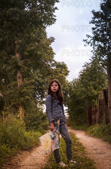 Caucasian teenage girl carrying kite on dirt road