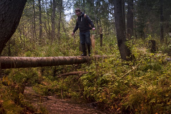 Caucasian man balancing on fallen tree