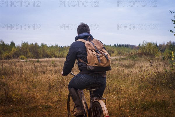 Caucasian man riding bicycle in field