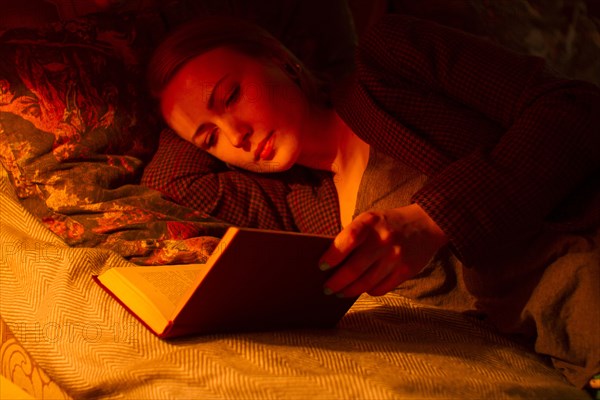 Caucasian woman reading book in bed