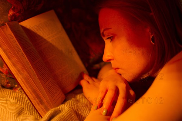 Caucasian woman reading book in bed