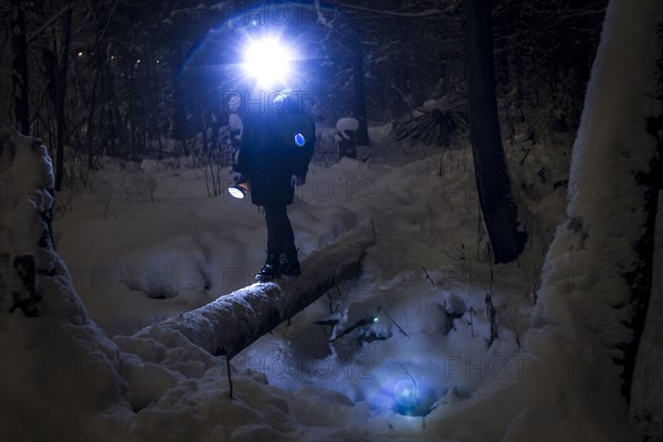 Caucasian hiker wearing headlamp balancing on forest log