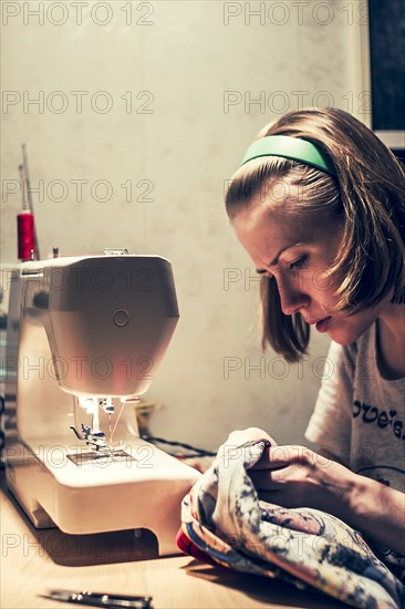 Caucasian woman using sewing machine