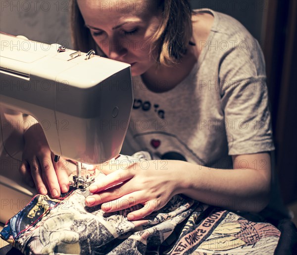 Caucasian woman using sewing machine