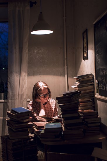 Caucasian woman reading stack of books