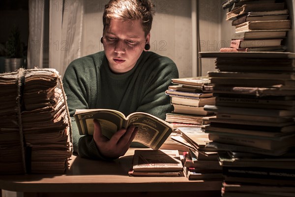 Caucasian man reading stack of books