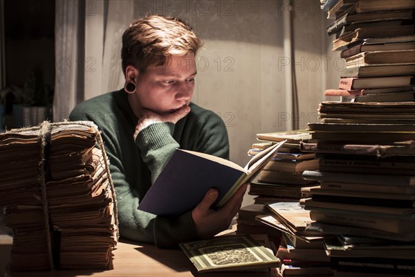 Caucasian man reading stack of books