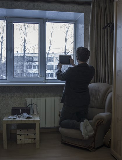 Caucasian man photographing with digital tablet in living room