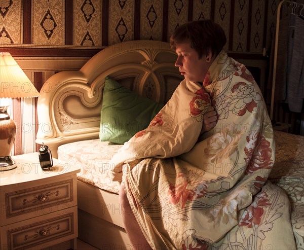 Caucasian man wrapped in blanket on bed