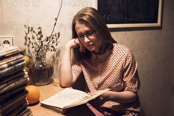 Caucasian woman reading book at kitchen table