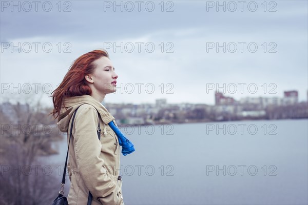 Woman with red hair standing at waterfront