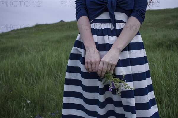 Caucasian woman holding wildflowers in field of grass