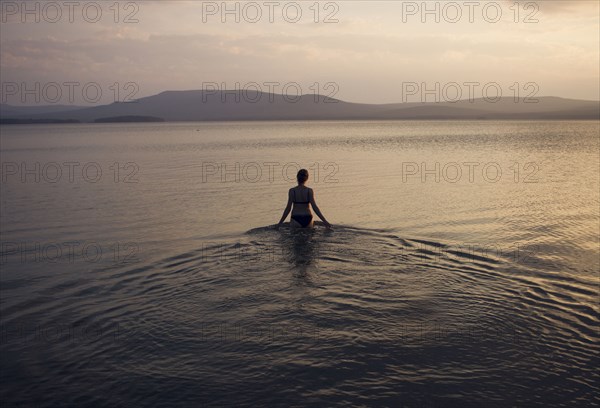 Silhouette of Caucasian woman wading in lake