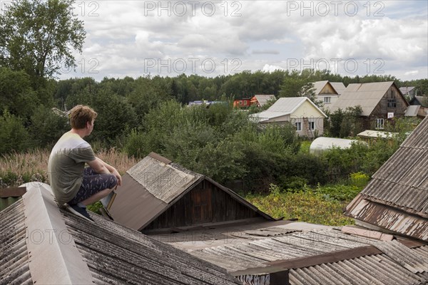 Caucasian man sitting on roof holding book