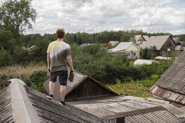 Caucasian man standing on roof holding book