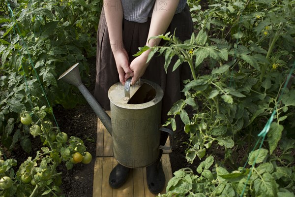 Caucasian woman holding watering can in greenhouse