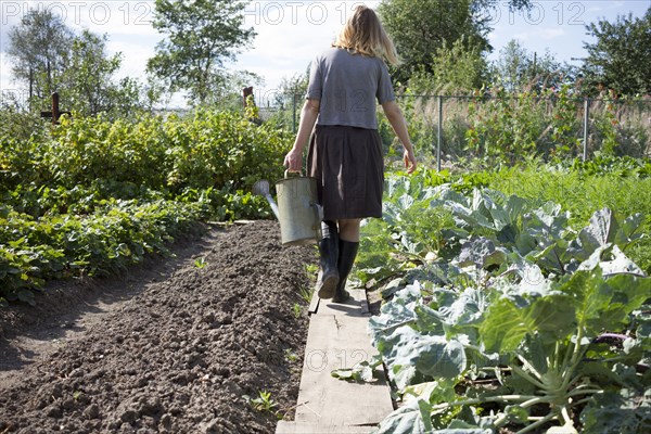 Caucasian woman carrying watering can in garden