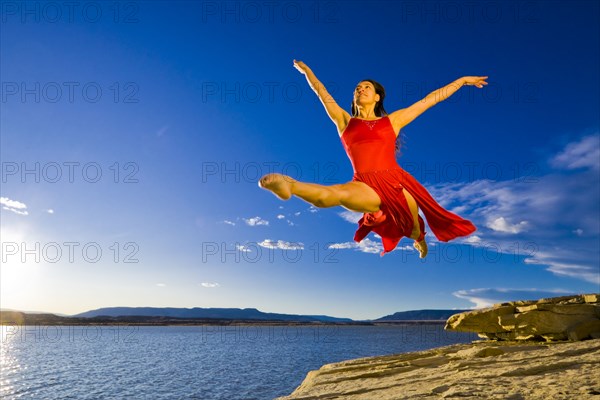 Hispanic woman dancing near lake