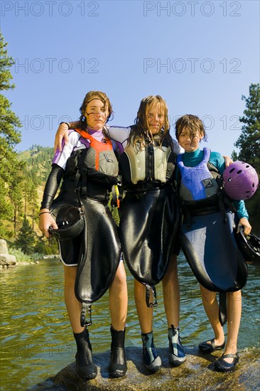 Wet Caucasian girls standing near river in kayak gear