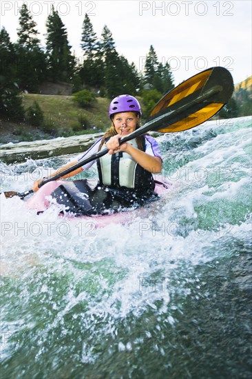 Caucasian teenager kayaking in river