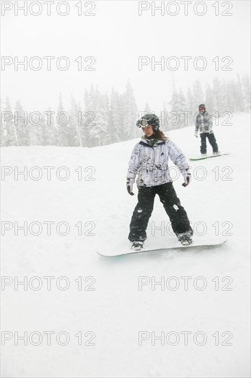 Snowboarders descending ski slope