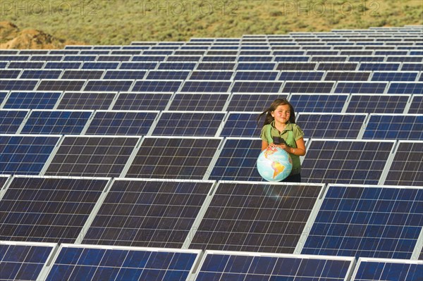 Native American girl standing near solar panels holding globe
