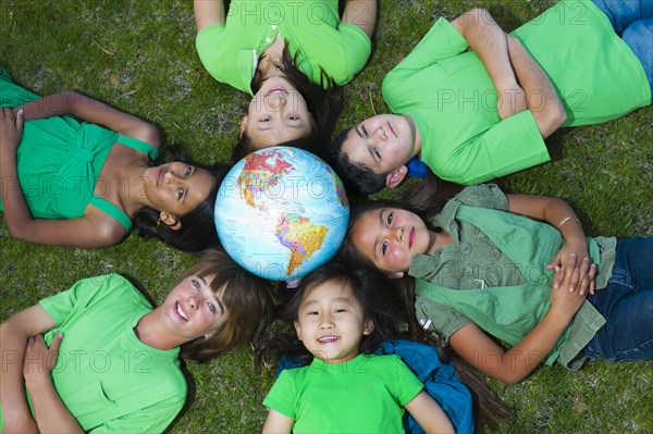 Children laying in grass around globe