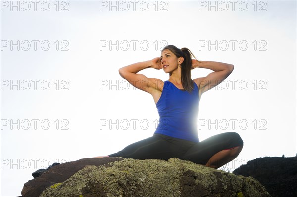 Hispanic woman stretching on rock