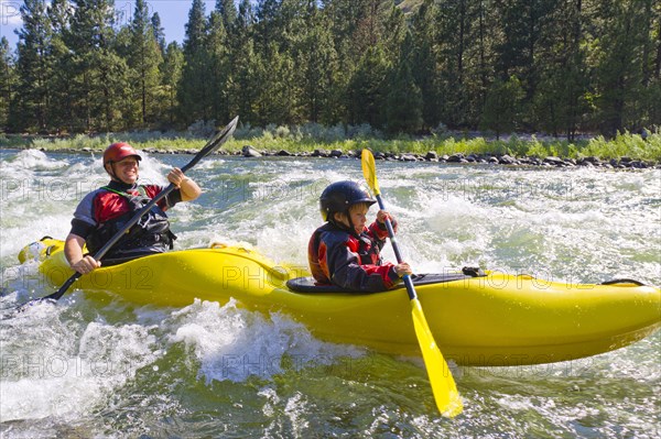 Caucasian father and son kayaking in river