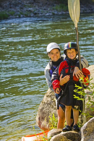 Caucasian mother and son with kayak near river