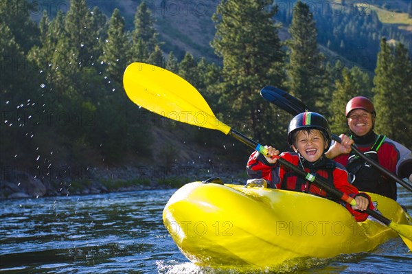 Caucasian father and son kayaking on river