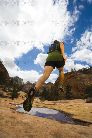 Persian woman jumping over canyon puddle