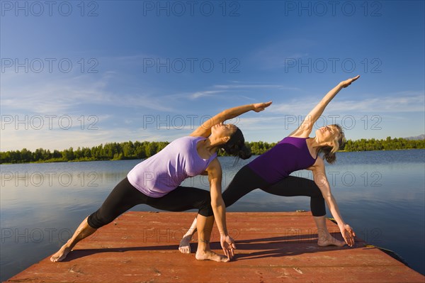 Women stretching on lake pier
