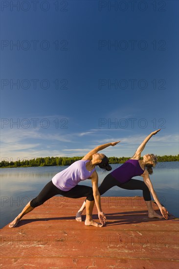 Women stretching on lake pier