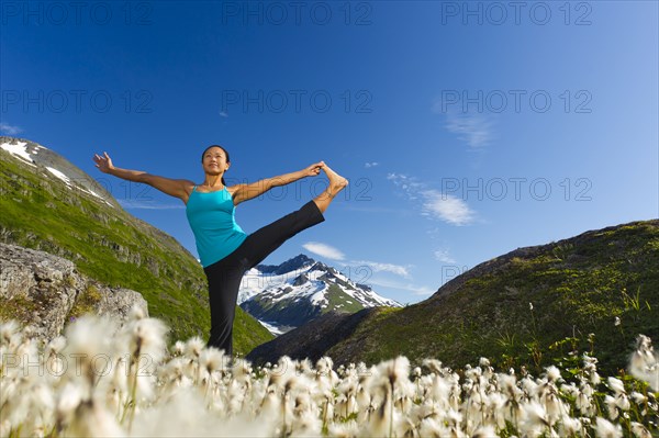 Korean woman practicing yoga with mountain in background